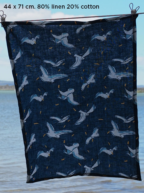 tea towel 80% linen 20% cotton very absorbent printed with a pattern of seagulls fighting over potato chips in the air on a dark blue back ground