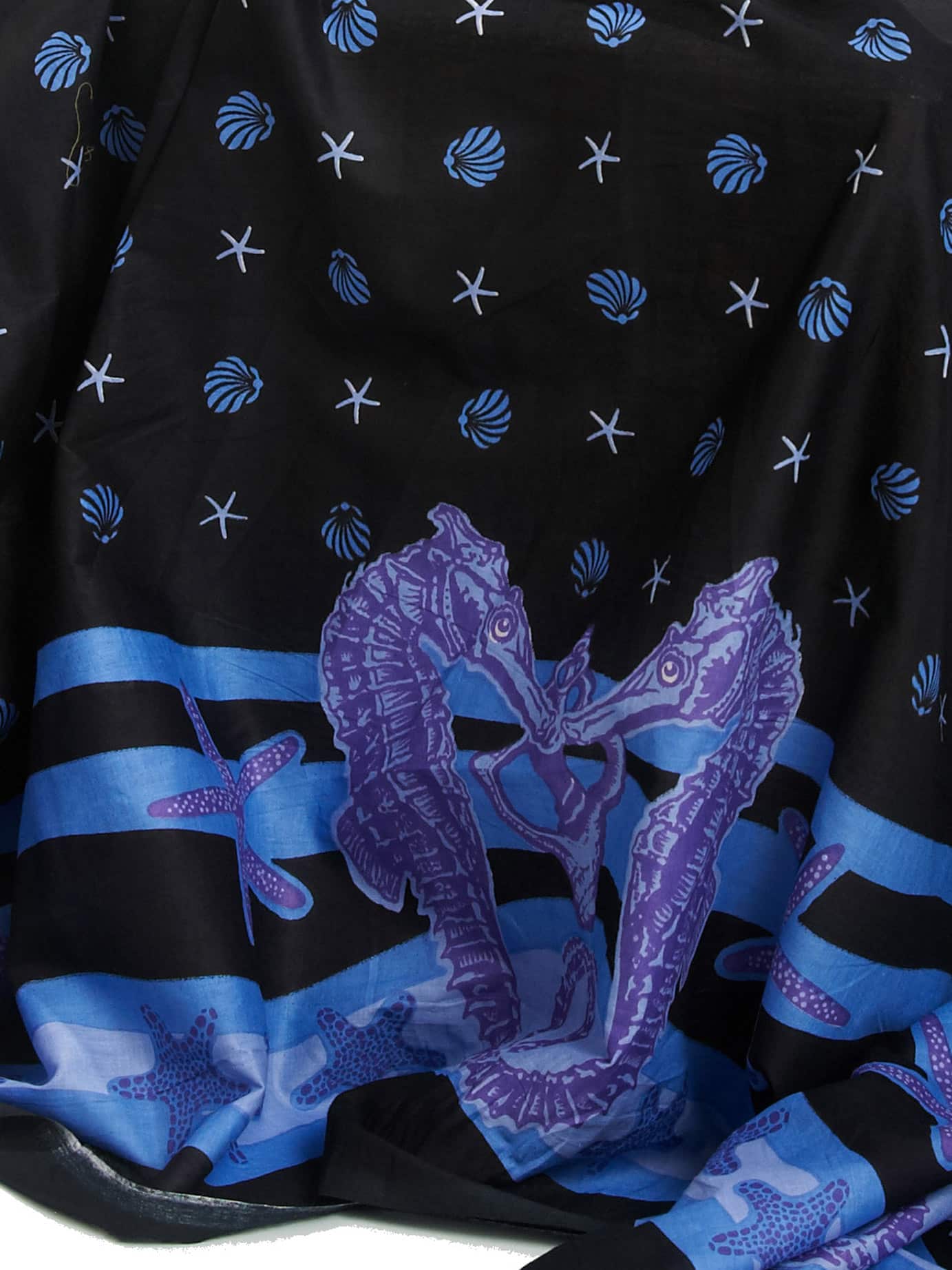 A cotton sarong printed with seahorses and shells on a black background.